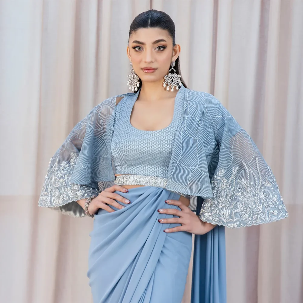 Occasion Styling "Sky Blue Fusion Saree styled for a wedding guest look, combining traditional embroidery and modern elements like the belt and organza cape."