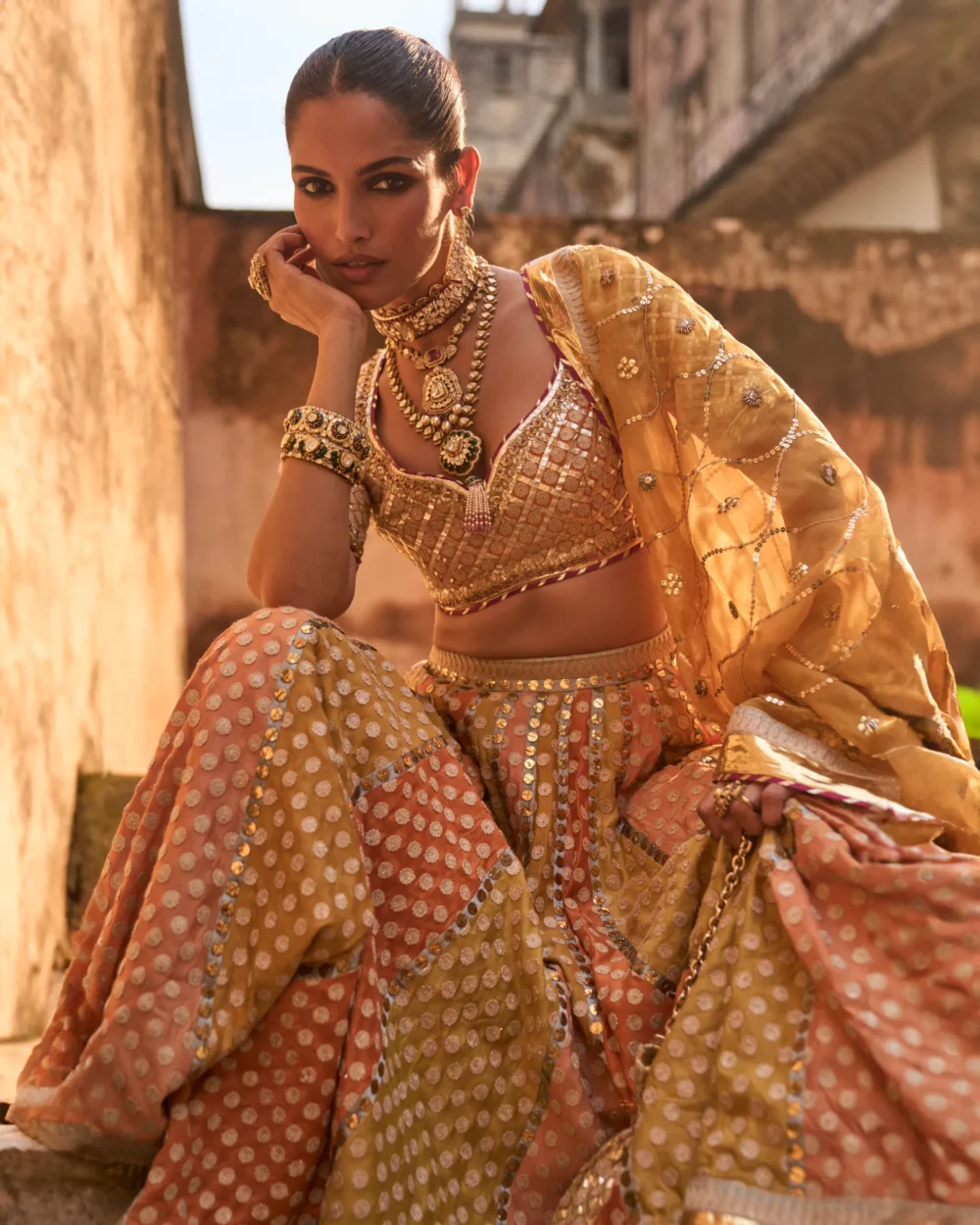 Khaddi Silk Lehenga Set featuring an orange blouse with gota work, a mustard lehenga with ari work panels, and a mustard organza dupatta.