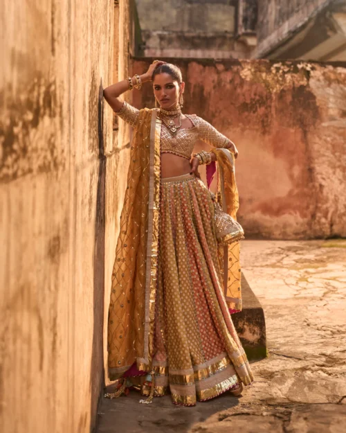 Khaddi Silk Lehenga Set featuring an orange blouse with gota work, a mustard lehenga with ari work panels, and a mustard organza dupatta.
