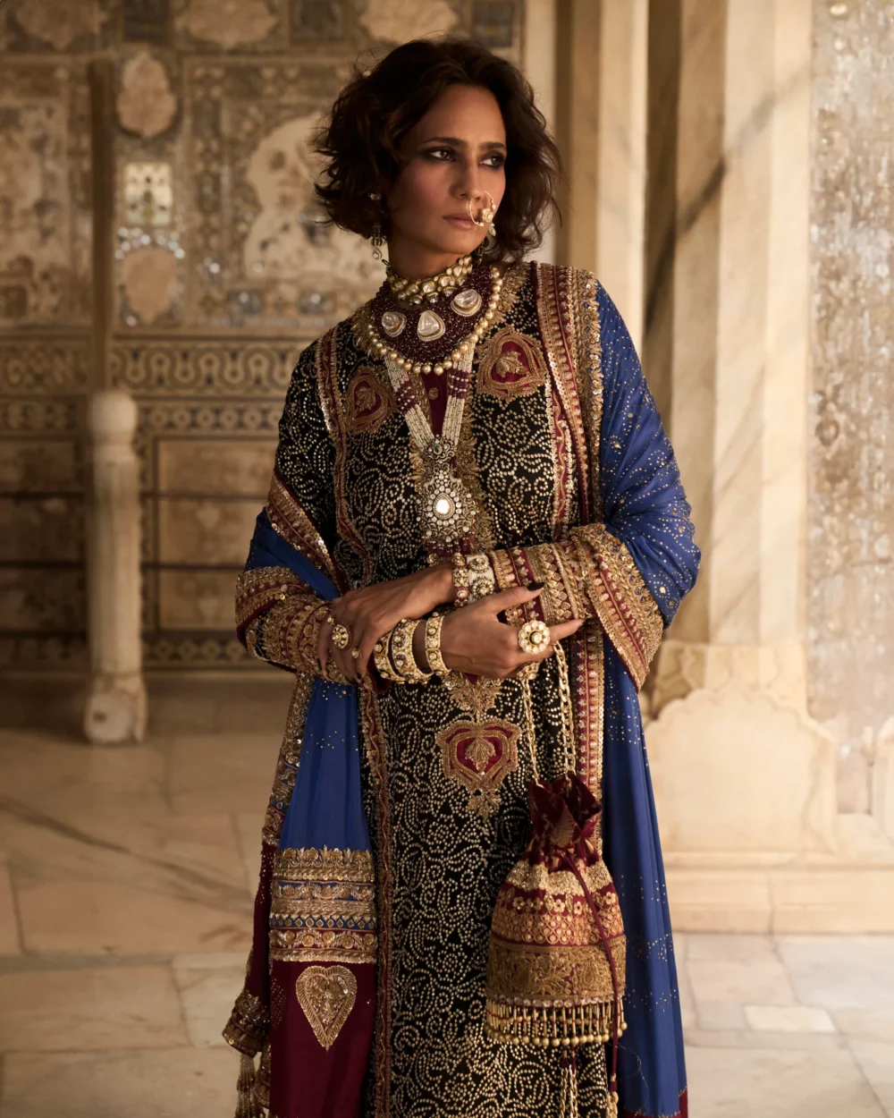The intricate details of the Black Charmeuse Chunri Lehenga Set are beautifully showcased as the model stands confidently.