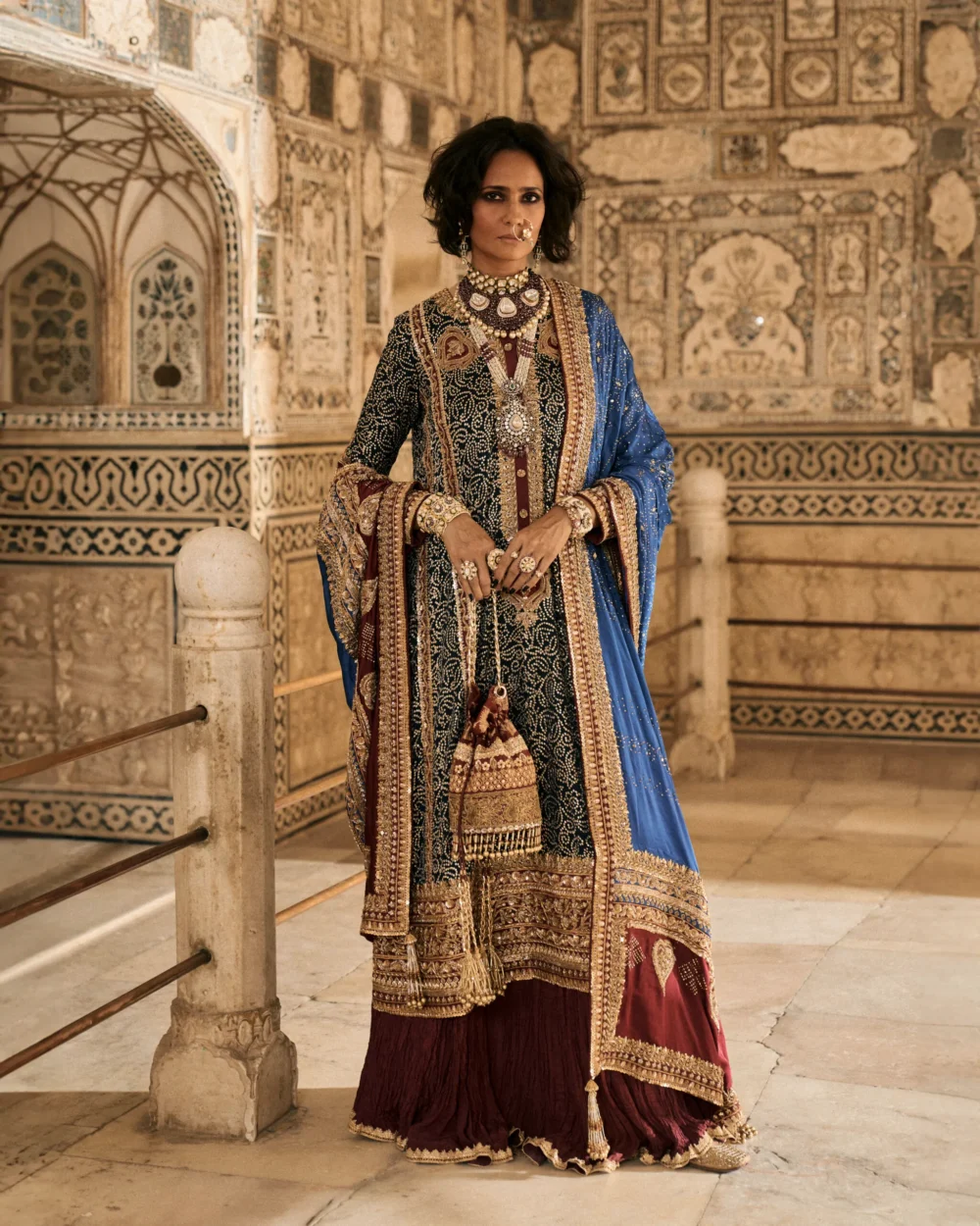 A woman gracefully poses in a stunning Black Charmeuse Chunri Lehenga Set, exuding elegance and sophistication.