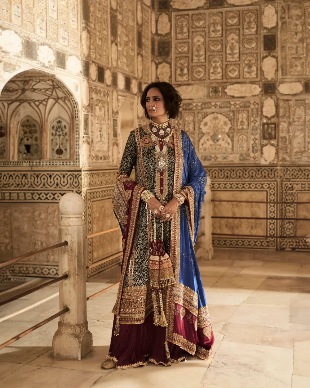 The model elegantly displays the Black Charmeuse Chunri Lehenga Set, capturing attention with its rich colors and detailed embroidery.