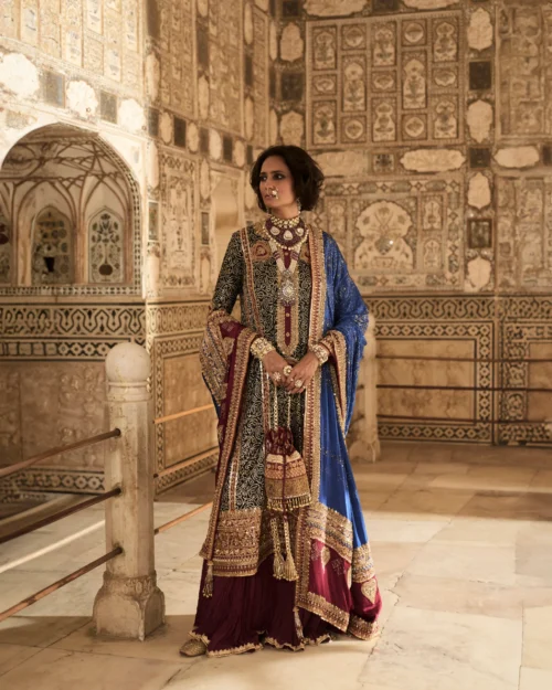 The model elegantly displays the Black Charmeuse Chunri Lehenga Set, capturing attention with its rich colors and detailed embroidery.