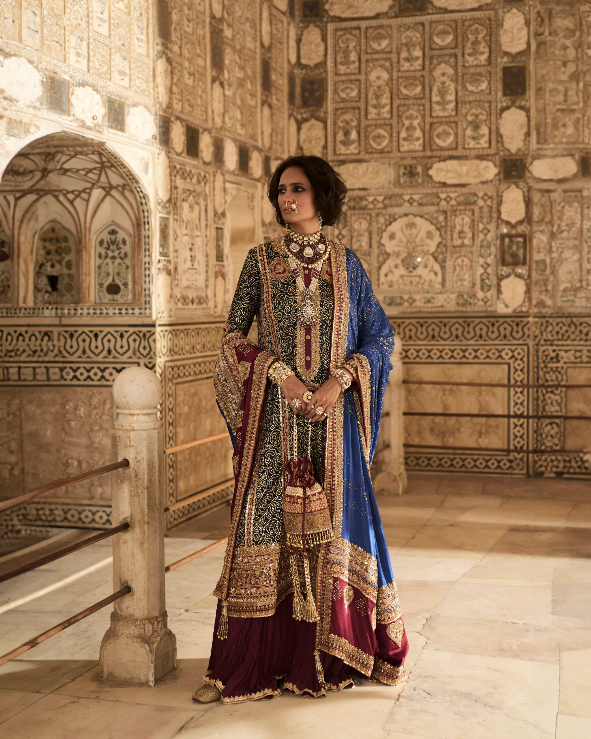 The model elegantly displays the Black Charmeuse Chunri Lehenga Set, capturing attention with its rich colors and detailed embroidery.